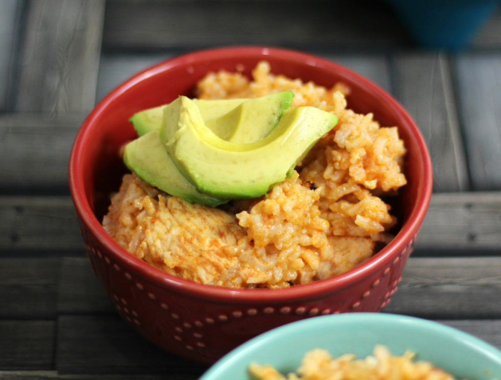 instant pot arroz con pollo in a red bowl with avocados