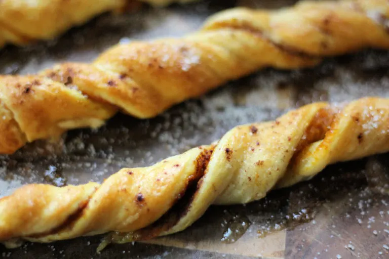 Pumpkin spice churros on a wooden serving board with a bowl of butter off to the right side.