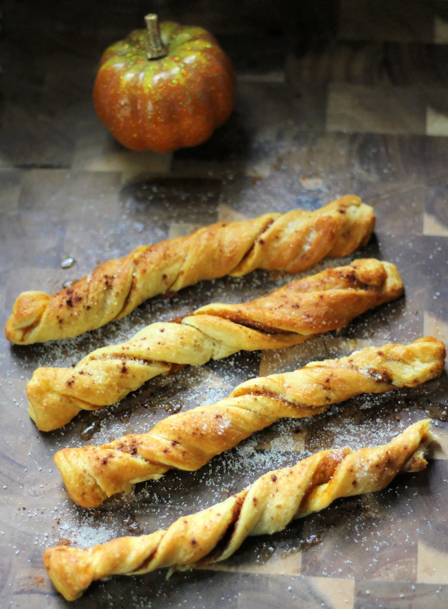 Pumpkin spice churros on a wooden serving board with a bowl of butter off to the right side.