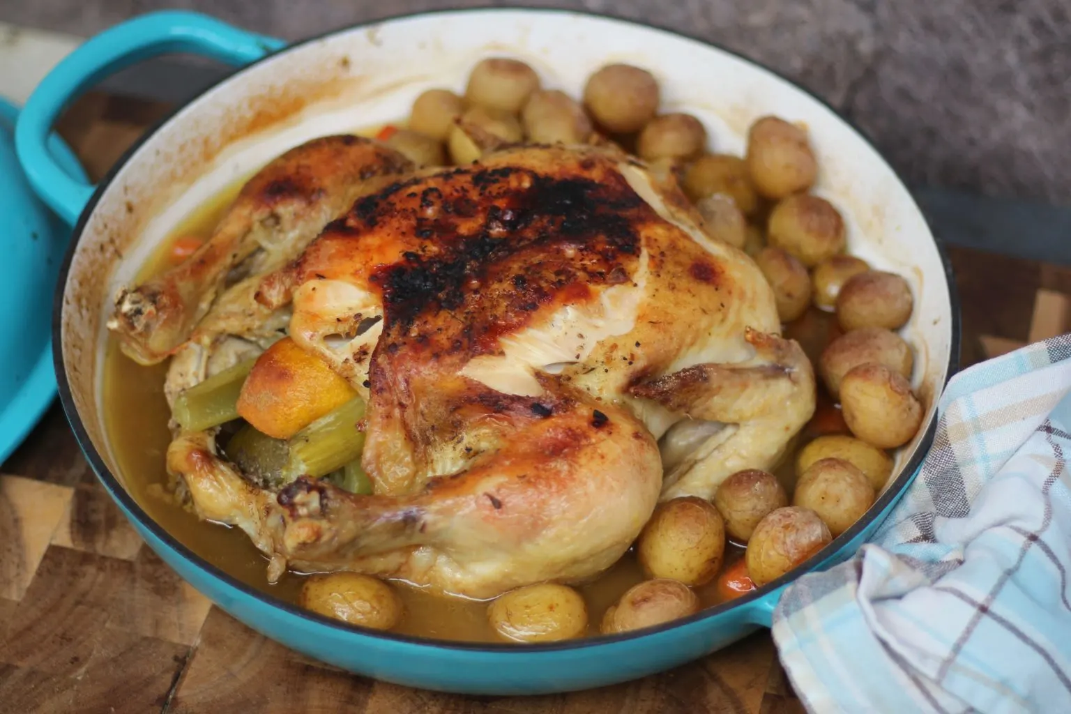 Roasted chicken and vegetables in a teal dish.
