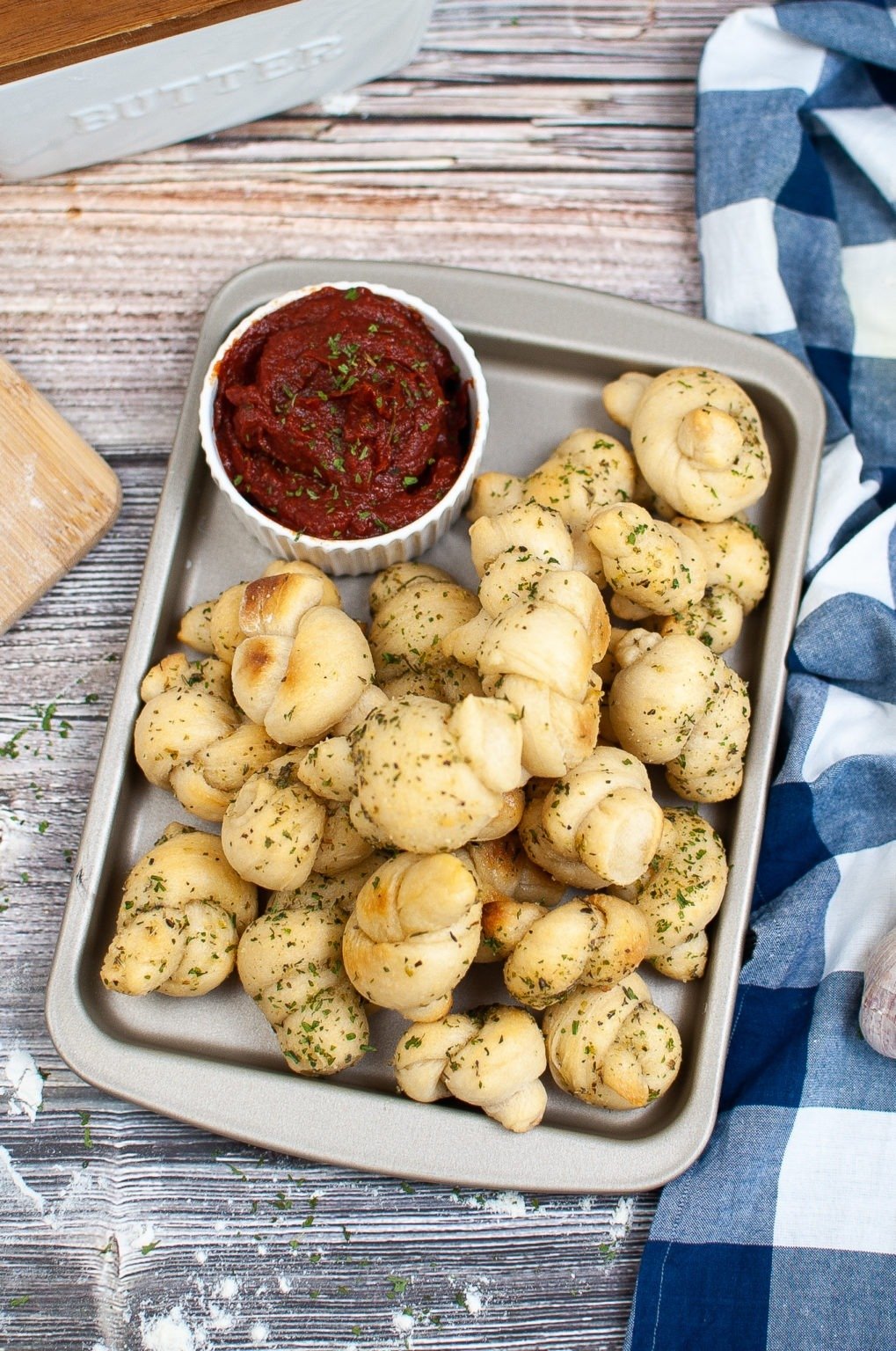 Pan of garlic knots with marinara sauce.