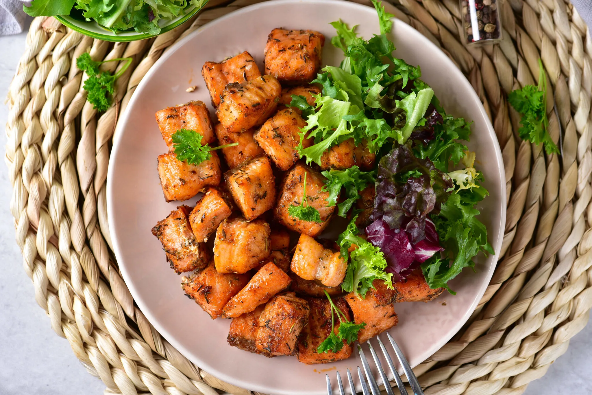 Plate of Salmon Bites with a salad and two forks.