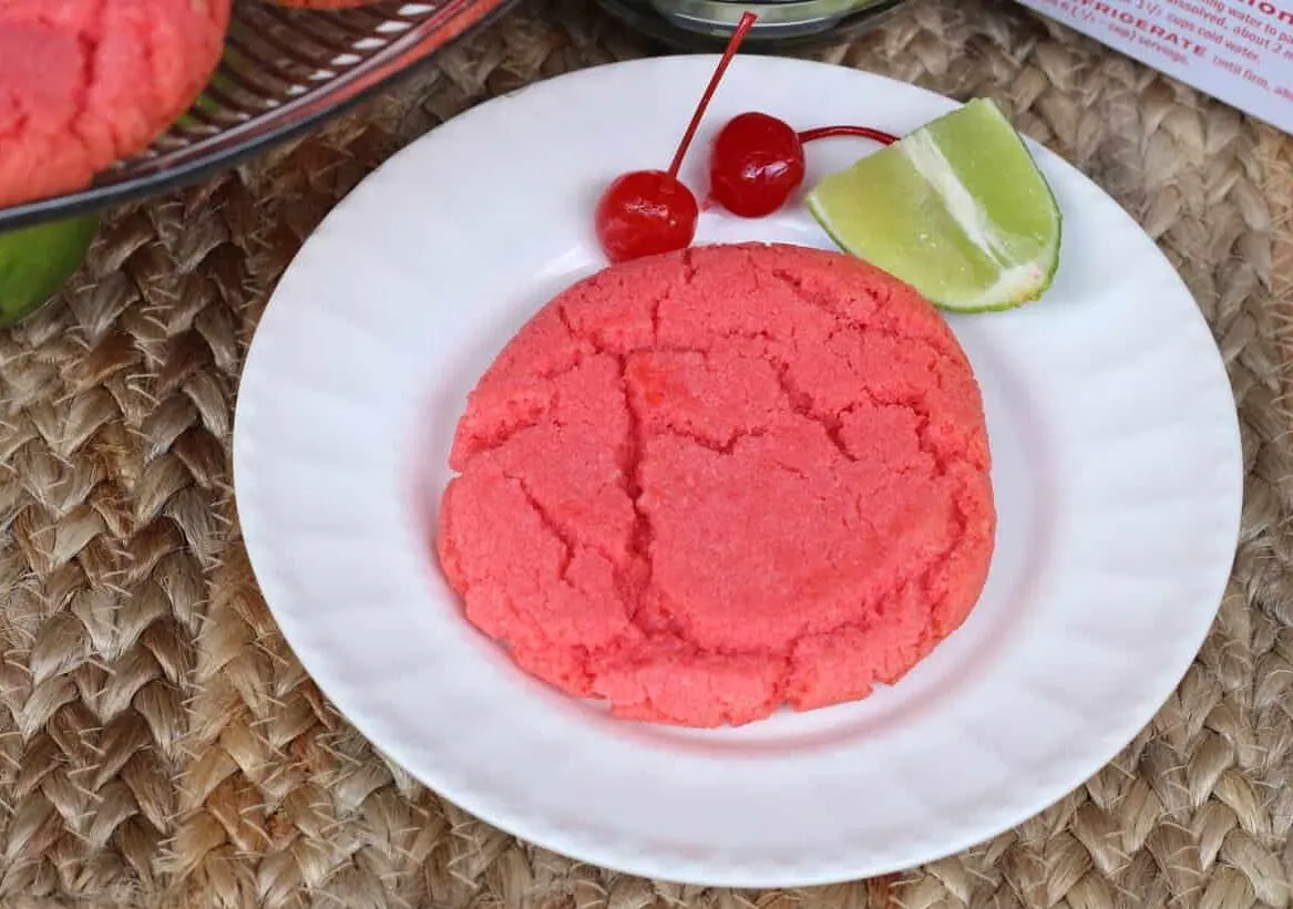 white plate with cherry limeade cookie, a lime slice, and cherries